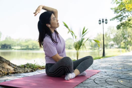 A woman performs a side stretch on a yoga mat, enhancing her wellness and flexibility in a peaceful outdoor environment.