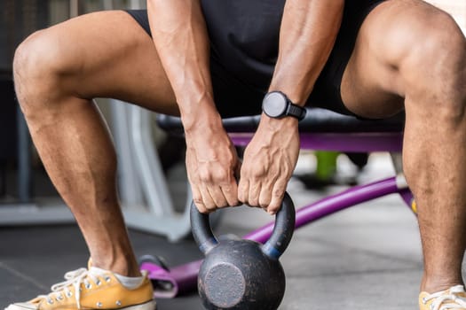 A focused individual grips a kettlebell, ready to engage in a strength training session, highlighting fitness and dedication.