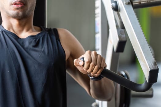 A focused male athlete engages in strength training using a machine, showcasing dedication and fitness.