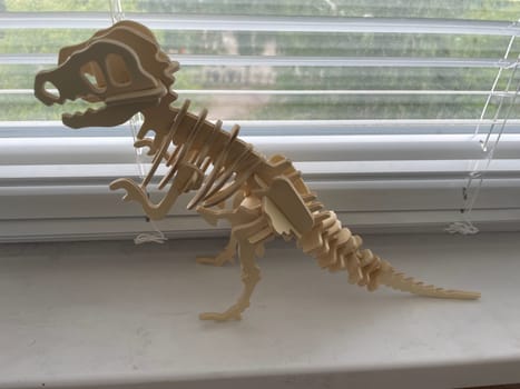 A handcrafted wooden dinosaur model displayed against a clean white background.