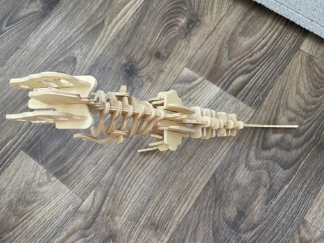 A handcrafted wooden dinosaur model displayed against a clean white background.