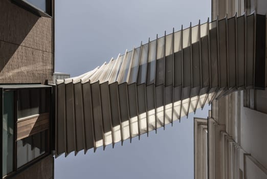 London, UK - May 13, 2025 - Looking up of The futuristic modern of Twisted sky bridge connecting Royal opera house to Royal ballet school in Covent garden. Exterior architectural design of Bridge of Aspiration with sky background, Stunning of Passageway between buildings, use it as your Wallpaper, Poster and Copy space, Selective focus.
