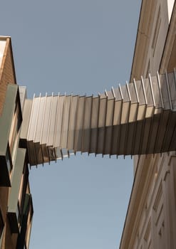 London, UK - May 13, 2025 - Looking up of Bridge of Aspiration with sky background, The futuristic modern of Twisted sky bridge connecting Royal opera house to Royal ballet school in Covent garden, Exterior architectural design of Passageway between buildings, use it as your Wallpaper, Poster and Copy space, Selective focus.