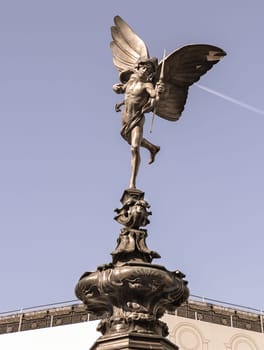 London, UK - May 13, 2025 - The Statue of Eros is The Greek god anteros (the Greek God of love)​ that sits atop of the Shaftesbury memorial fountain is bronze with sky in the background, is a cast aluminium sculpture with winged poised in Piccadilly circus. use it as your Wallpaper, Poster and Space for text, Selective focus.