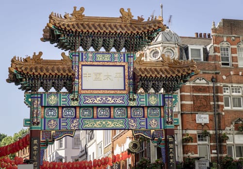 London, UK - May 13, 2025 - Beautiful view of London Chinatown entrance gate in traditional chinese design with glazed yellow tiles, a golden dragon, painted panels, two white jade plaques and red lanterns, The Chinese text translates "Peace and Prosperity (Zhong guo tai ping) to Chinatown". use it as your Wallpaper, Poster and Space for text, Selective focus.