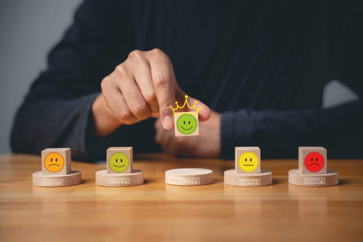 Hand of a businessman selecting a smiley face on a wooden block for the best customer experience. Satisfaction survey and feedback concept. 5-star satisfaction is guaranteed.