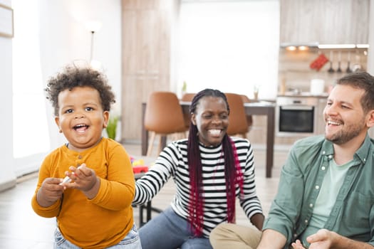 A joyful multiracial family plays together in their cozy living room.