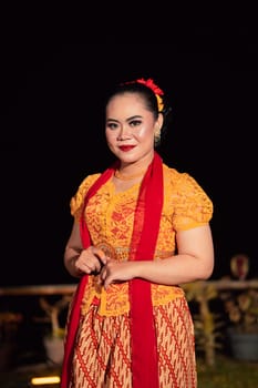 Cute Indonesian woman with red lips and a red scarf wearing a traditional Sundanese dress called kebaya inside the dance festival