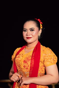 Cute Indonesian woman with red lips and a red scarf wearing a traditional Sundanese dress called kebaya inside the dance festival