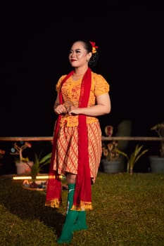 Cute Indonesian woman with red lips and a red scarf wearing a traditional Sundanese dress called kebaya inside the dance festival