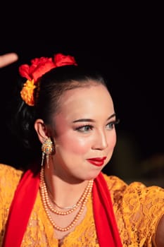 Beautiful Asian woman with makeup and flower accessories on her hair while wearing gold jewelry in the night