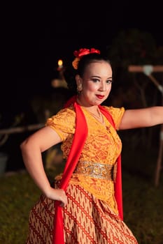 Beautiful Javanese woman with a golden necklace on her neck and golden belt on a yellow dress on their body during the dance performance