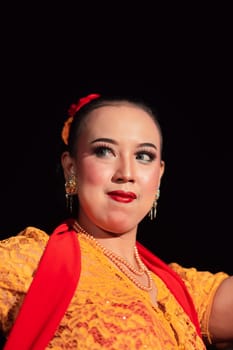 Indonesian woman in makeup with red lips wearing a golden necklace and golden earrings before dancing on the stage