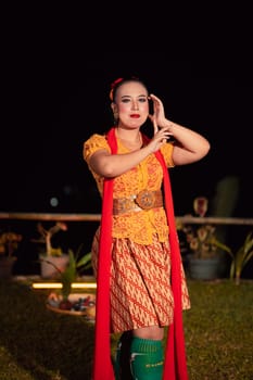 Beautiful Javanese woman with a golden necklace on her neck and golden belt on a yellow dress on their body during the dance performance