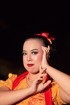 Indonesian woman in makeup with red lips wearing a golden necklace and golden earrings before dancing on the stage
