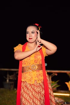 Beautiful Javanese woman with a golden necklace on her neck and golden belt on a yellow dress on their body during the dance performance