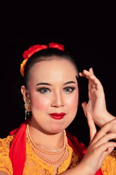 Indonesian woman in makeup with red lips wearing a golden necklace and golden earrings before dancing on the stage
