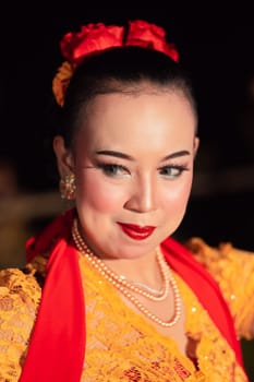 Beautiful Asian woman with makeup and flower accessories on her hair while wearing gold jewelry in the night