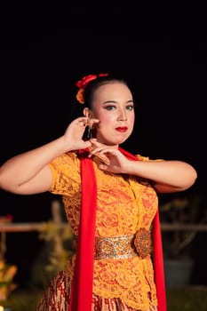 Beautiful Javanese woman with a golden necklace on her neck and golden belt on a yellow dress on their body during the dance performance