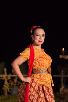 Sexy Balinese woman with makeup while wearing an orange dress called kebaya posing bravely after dancing in the village