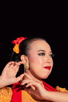 Exotic Javanese woman wearing beautiful makeup with red lips while wearing a traditional yellow costume and red scarf inside the village