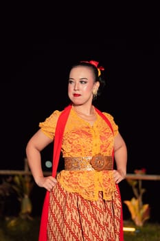 Sexy Balinese woman with makeup while wearing an orange dress called kebaya posing bravely after dancing in the village