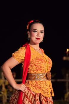 Sexy Balinese woman with makeup while wearing an orange dress called kebaya posing bravely after dancing in the village