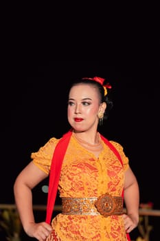 Sexy Balinese woman with makeup while wearing an orange dress called kebaya posing bravely after dancing in the village