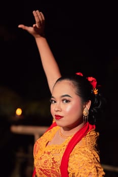 The beautiful closeup face of a Javanese woman with make-up at a traditional dance performance while wearing a yellow costume in the village