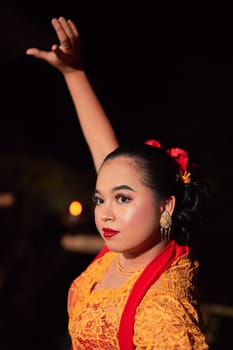 The beautiful closeup face of a Javanese woman with make-up at a traditional dance performance while wearing a yellow costume in the village