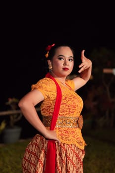 Balinese dancers in yellow color traditional costumes present the dance in front of visitors in a Bali dance performance