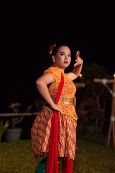 Balinese dancers in yellow color traditional costumes present the dance in front of visitors in a Bali dance performance