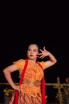 Balinese dancers in yellow color traditional costumes present the dance in front of visitors in a Bali dance performance