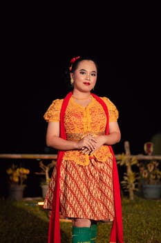Sundanese woman wearing a short dress and traditional yellow dress with red scarf and makeup after the dance performance on the stage