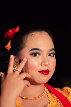 Beautiful face of an Asian woman with red lips and makeup in Indonesian traditional dance costume after the dance performance in the stage
