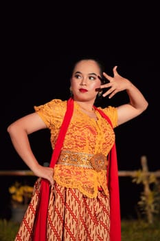 Balinese dancers in yellow color traditional costumes present the dance in front of visitors in a Bali dance performance