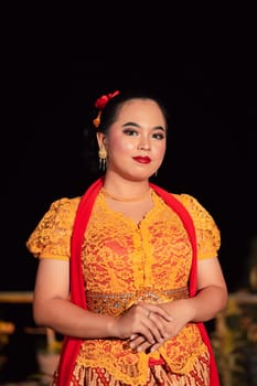 Sundanese woman wearing a short dress and traditional yellow dress with red scarf and makeup after the dance performance on the stage