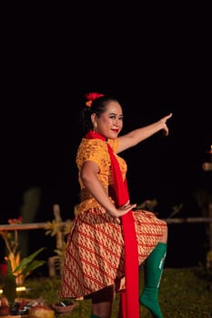 Asian woman performing a traditional dance called jaipong in Indonesia with a yellow dress and red scarf at the dance festival
