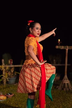 Asian woman performing a traditional dance called jaipong in Indonesia with a yellow dress and red scarf at the dance festival