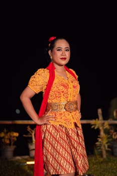 Beautiful Indonesian women wearing an orange traditional dance costume called kebaya when dancing a danced called jaipong inside the festival