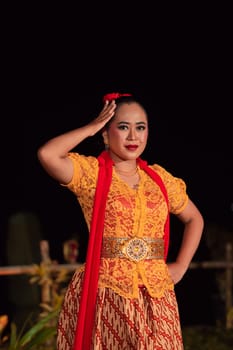Beautiful Indonesian women wearing an orange traditional dance costume called kebaya when dancing a danced called jaipong inside the festival