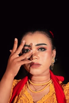 Gorgeous Asian woman wearing makeup and flowers in her hair while wearing a traditional orange dress and red scarf on her body at the night