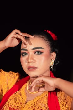 Gorgeous Asian woman wearing makeup and flowers in her hair while wearing a traditional orange dress and red scarf on her body at the night