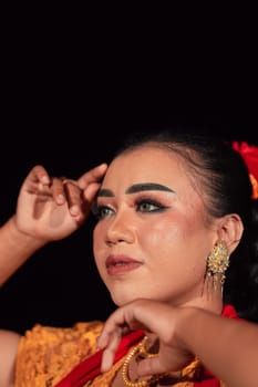 a Sharp gaze from an Indonesian woman with makeup on her face while wearing an orange dress and golden earrings in the night