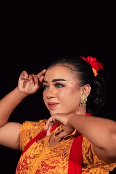 a Sharp gaze from an Indonesian woman with makeup on her face while wearing an orange dress and golden earrings in the night