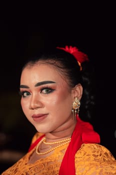 Sharp eyes from Indonesian women with makeup while wearing an orange dress at the dancing festival in the night