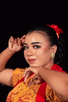 a Sharp gaze from an Indonesian woman with makeup on her face while wearing an orange dress and golden earrings in the night