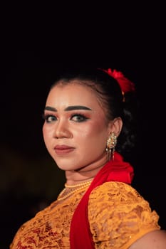 Sharp eyes from Indonesian women with makeup while wearing an orange dress at the dancing festival in the night