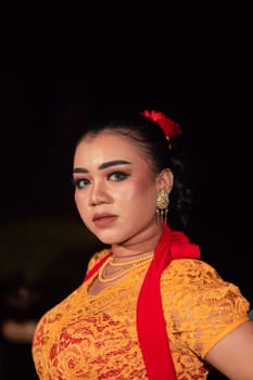 Sharp eyes from Indonesian women with makeup while wearing an orange dress at the dancing festival in the night