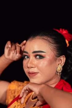 a Sharp gaze from an Indonesian woman with makeup on her face while wearing an orange dress and golden earrings in the night